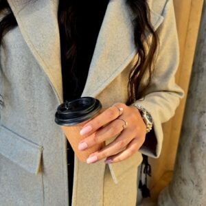 زنی با کت فوتر ، شلوار مشکی و بوت کرم‌رنگ در فضایی کلاسیک ایستاده است؛ کت با طراحی مینیمال و پارچه گرم و مناسب فصل پاییز و زمستان.